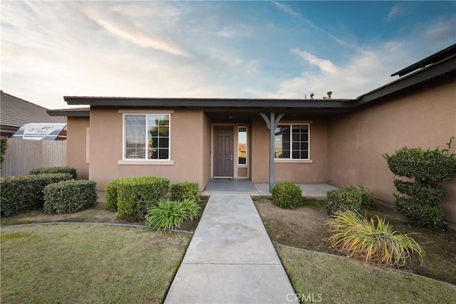 doorway to property with a patio and a lawn