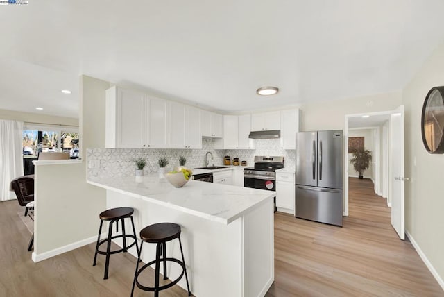 kitchen featuring sink, light wood-type flooring, kitchen peninsula, stainless steel appliances, and white cabinets