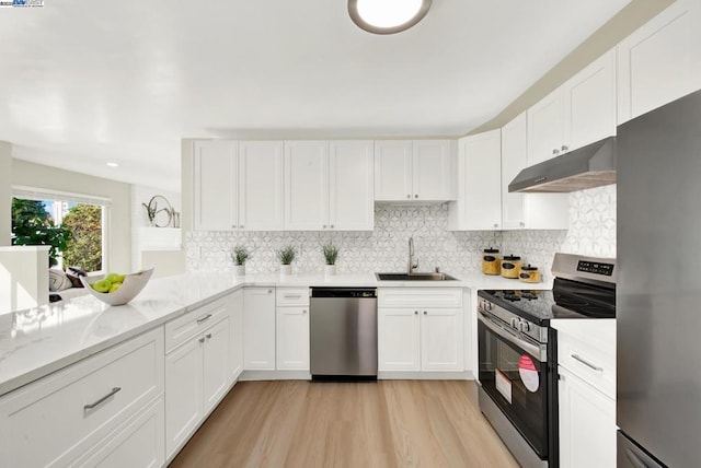 kitchen with sink, light hardwood / wood-style flooring, appliances with stainless steel finishes, white cabinetry, and light stone countertops