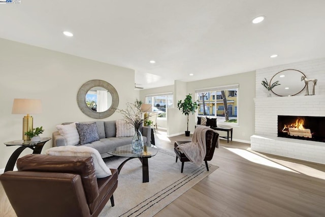 living room featuring a brick fireplace and light hardwood / wood-style flooring