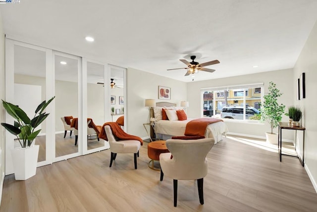 bedroom featuring multiple closets, ceiling fan, and light hardwood / wood-style flooring