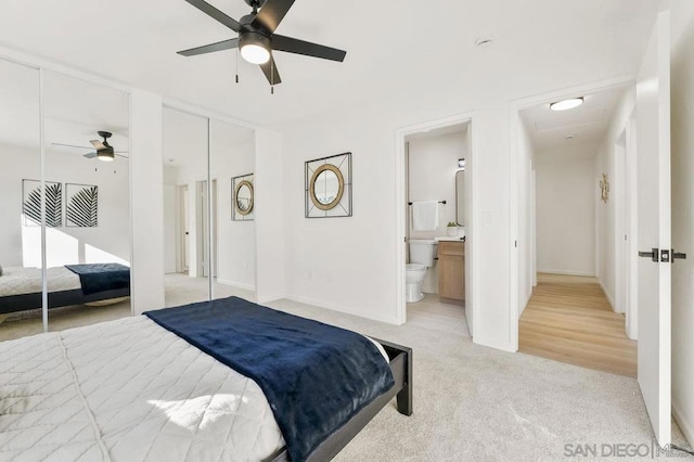 bedroom with ceiling fan, ensuite bathroom, and light colored carpet