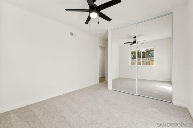 unfurnished bedroom featuring ceiling fan, light carpet, and a closet