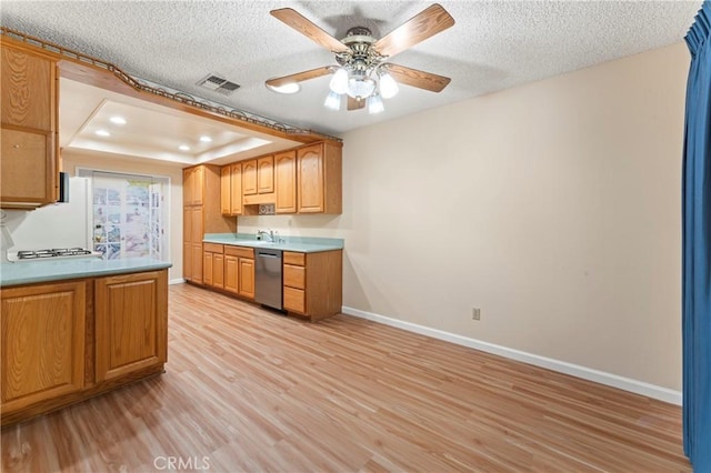 kitchen with dishwasher, a textured ceiling, a raised ceiling, and light hardwood / wood-style flooring