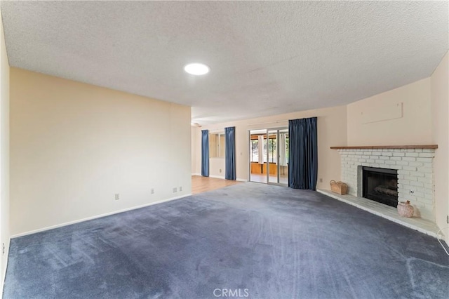 unfurnished living room featuring a textured ceiling, a brick fireplace, and dark colored carpet