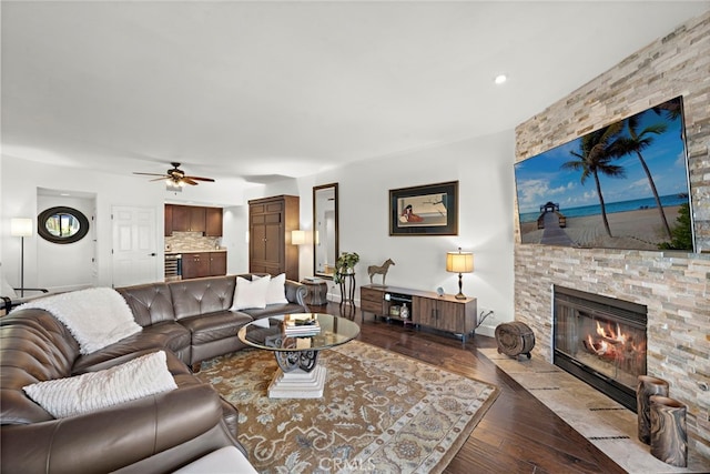 living room with a stone fireplace, ceiling fan, and light hardwood / wood-style flooring