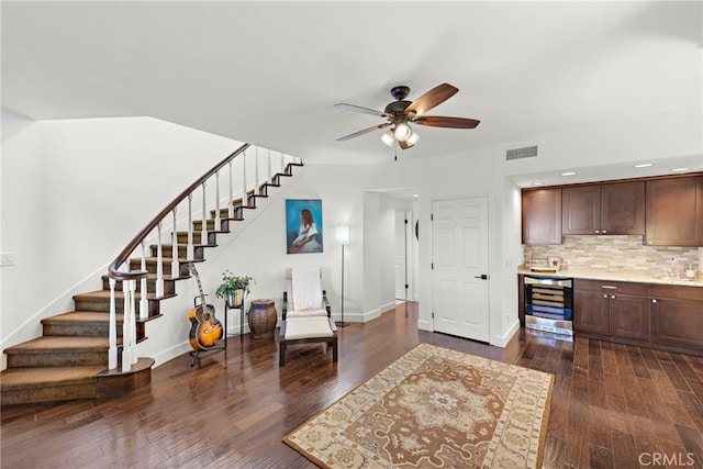 living room with dark wood-type flooring, ceiling fan, and beverage cooler