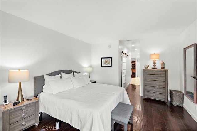 bedroom with dark hardwood / wood-style flooring and a barn door