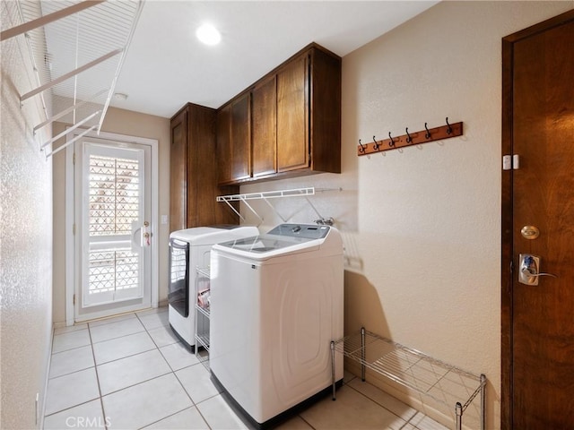 laundry area featuring cabinets, washing machine and dryer, and light tile patterned floors