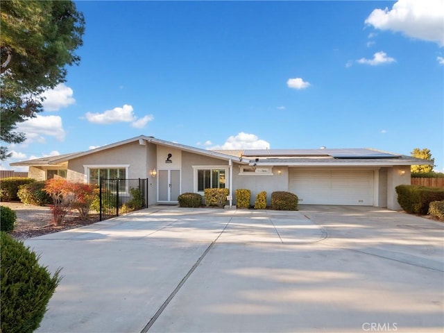 ranch-style house featuring a garage and solar panels