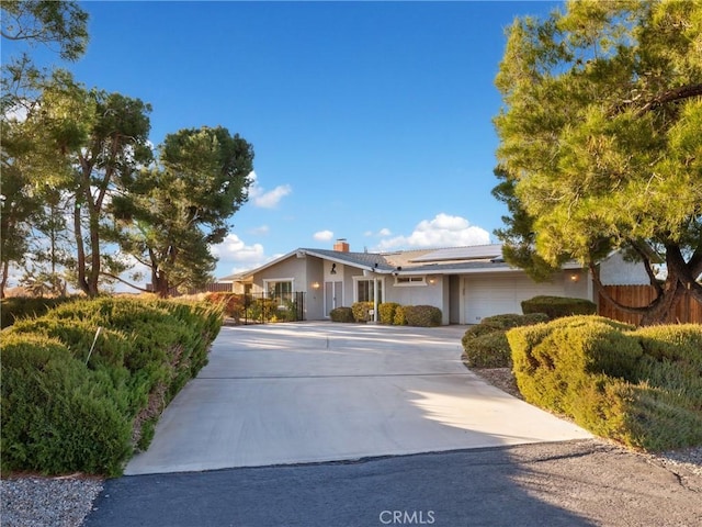 ranch-style house with a garage and solar panels