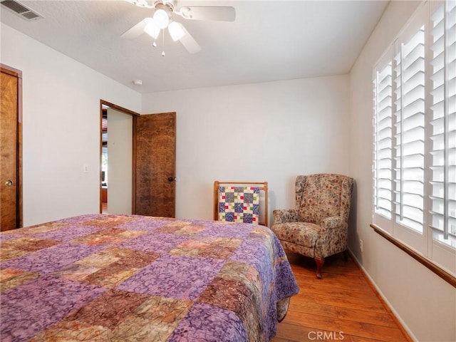 bedroom with multiple windows, hardwood / wood-style floors, and ceiling fan