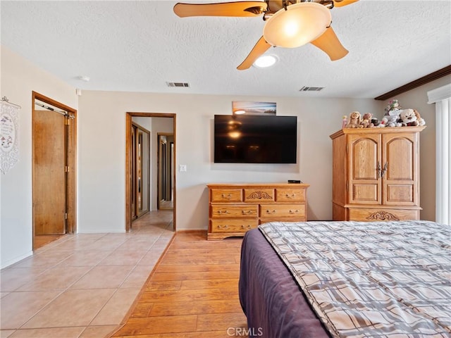 bedroom with light tile patterned flooring, ceiling fan, a closet, and a textured ceiling