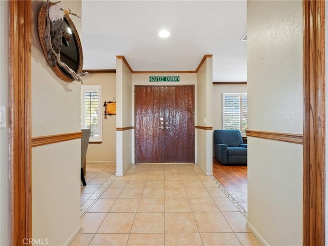 entrance foyer with light tile patterned floors and crown molding