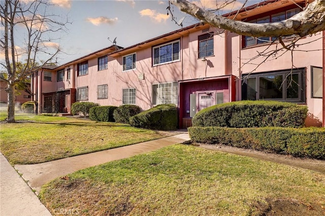 multi unit property featuring a front lawn and stucco siding