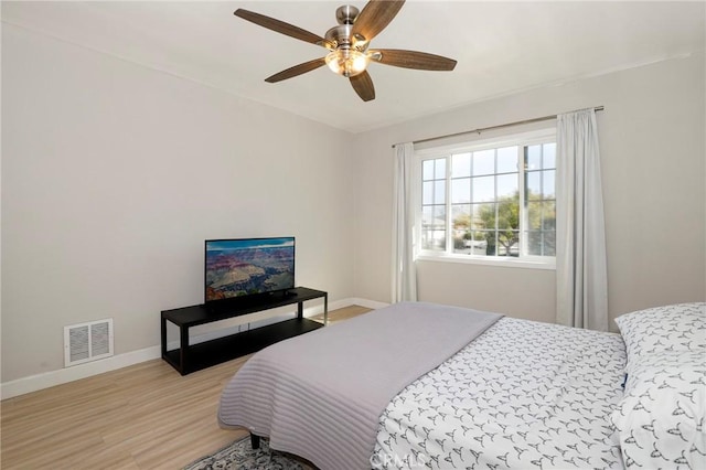 bedroom with a ceiling fan, light wood-type flooring, visible vents, and baseboards