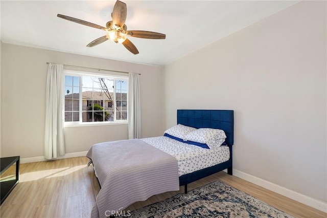 bedroom featuring ceiling fan, light wood-style flooring, and baseboards