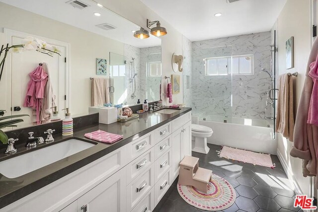 full bathroom featuring vanity, shower / bath combination with glass door, toilet, and a healthy amount of sunlight