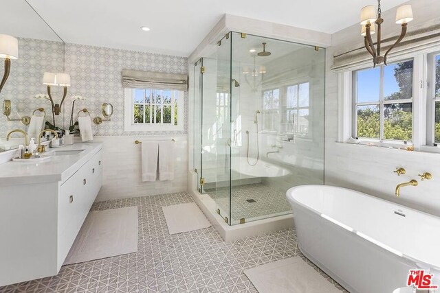 bathroom featuring tile walls, a chandelier, independent shower and bath, and a healthy amount of sunlight