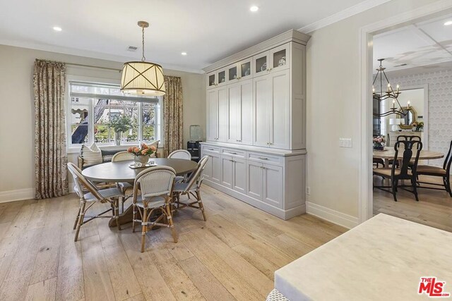 dining room featuring ornamental molding, a chandelier, and light hardwood / wood-style flooring