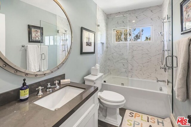 full bathroom featuring vanity, shower / bath combination with glass door, and toilet