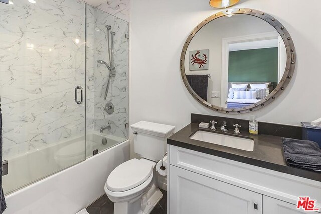 full bathroom with vanity, enclosed tub / shower combo, and toilet