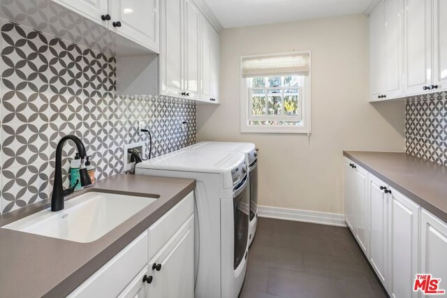 laundry room with cabinets, dark tile patterned flooring, sink, and washing machine and clothes dryer