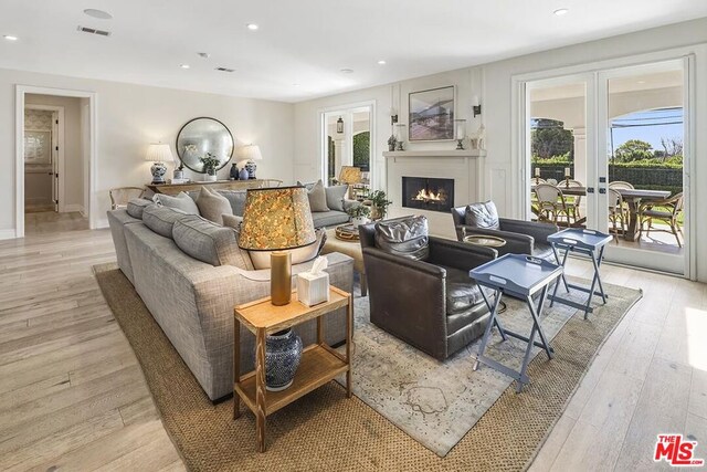 living room with a healthy amount of sunlight, light hardwood / wood-style floors, and french doors