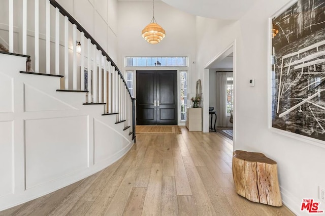 entrance foyer with a towering ceiling and light wood-type flooring