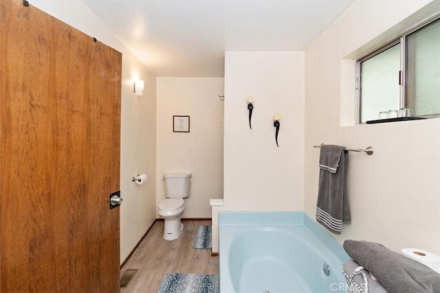 bathroom featuring hardwood / wood-style flooring, toilet, and a tub