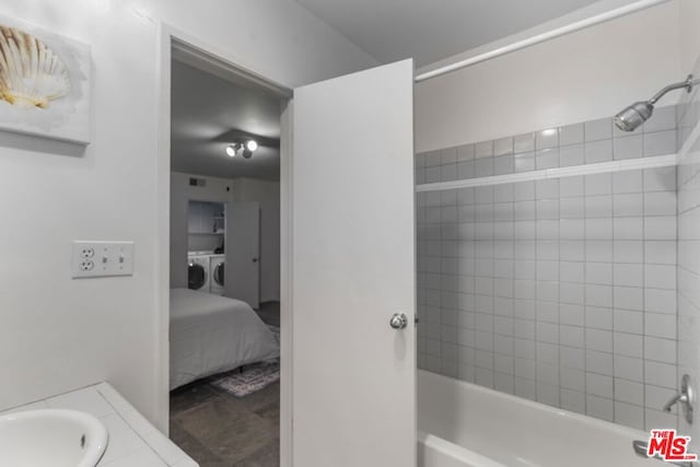 bathroom featuring tiled shower / bath, washing machine and clothes dryer, and vanity