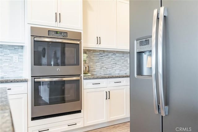 kitchen with appliances with stainless steel finishes, white cabinets, and light stone counters