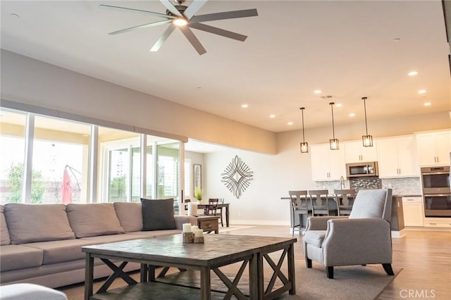 living room with ceiling fan and light hardwood / wood-style floors