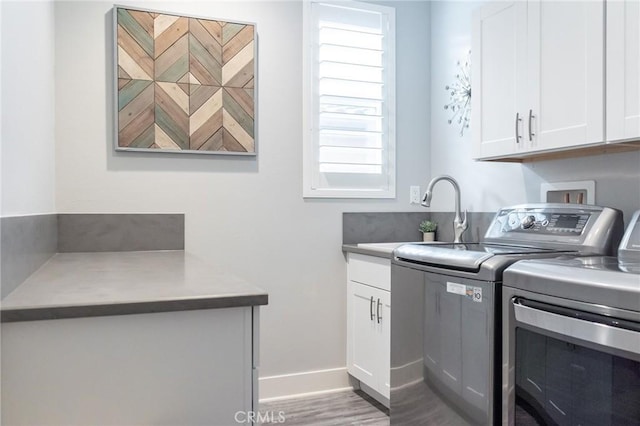 laundry room with sink, wood-type flooring, cabinets, and washing machine and clothes dryer