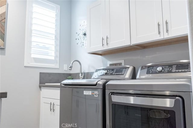 clothes washing area featuring cabinets and washer and clothes dryer