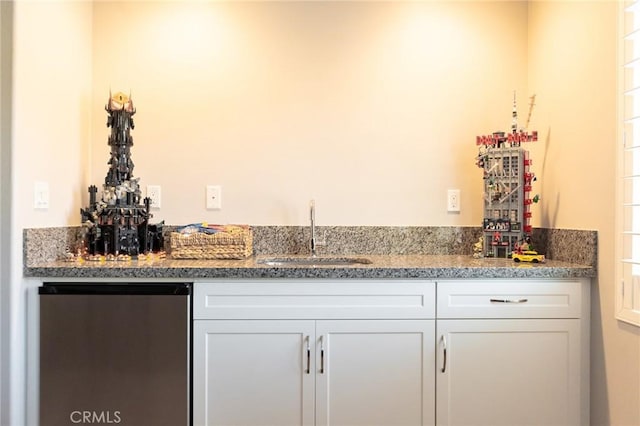 bar featuring stainless steel refrigerator, stone countertops, sink, and white cabinets