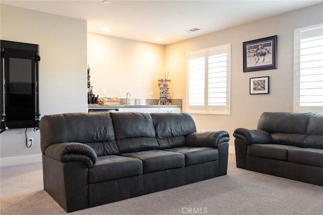 carpeted living room with a healthy amount of sunlight and wet bar