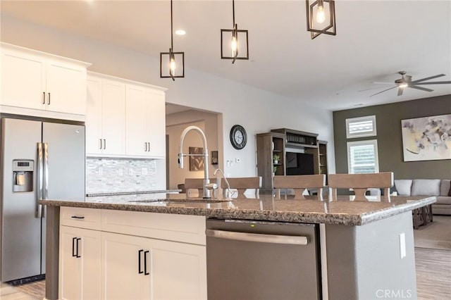 kitchen with decorative light fixtures, light wood-type flooring, white cabinets, and appliances with stainless steel finishes