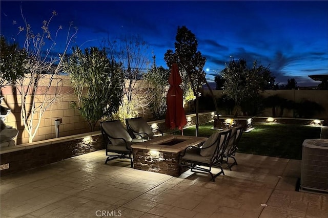 patio terrace at dusk with central AC and an outdoor fire pit