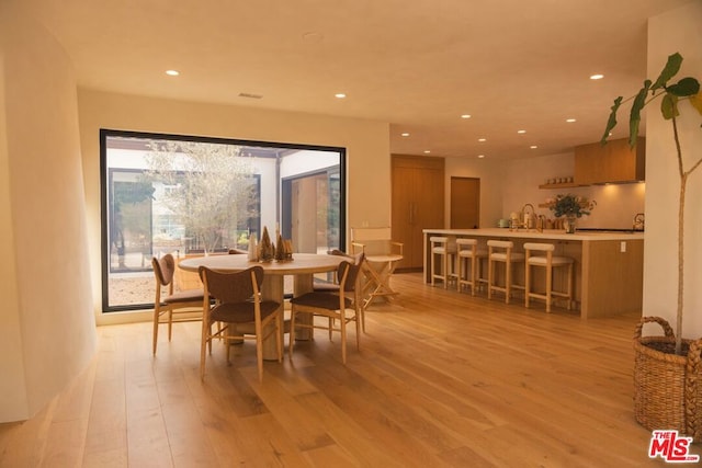 dining space with sink and light wood-type flooring