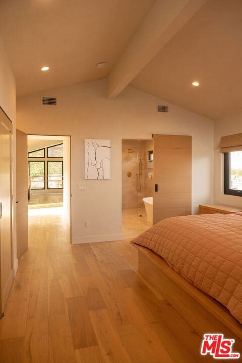 unfurnished bedroom featuring hardwood / wood-style floors, connected bathroom, and lofted ceiling with beams