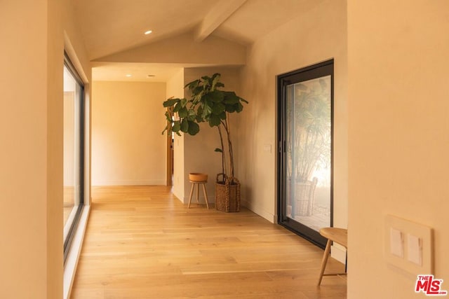 corridor featuring a healthy amount of sunlight, lofted ceiling with beams, and light wood-type flooring