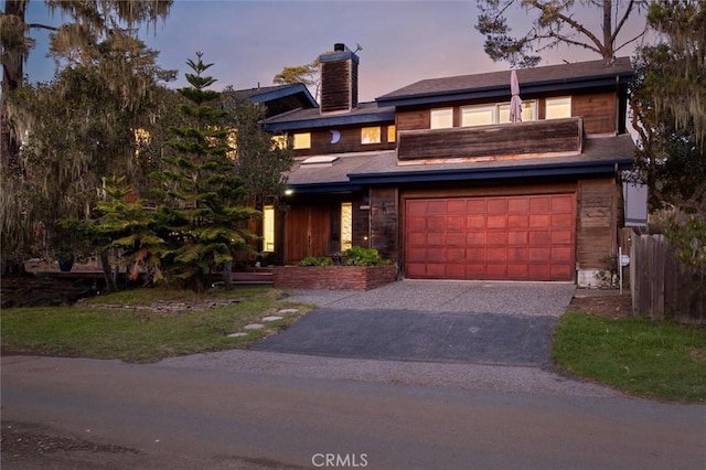 view of front facade with a garage, aphalt driveway, and a chimney