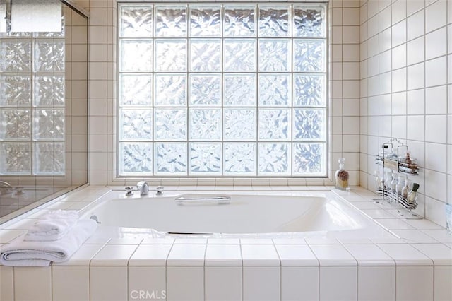 full bath with a garden tub, tile walls, and a healthy amount of sunlight