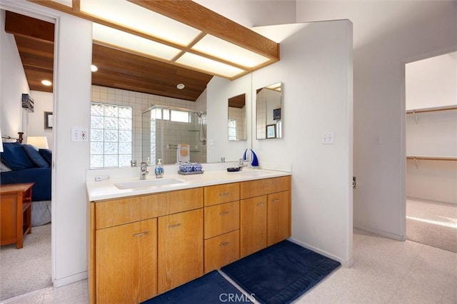 ensuite bathroom with double vanity, baseboards, ensuite bath, a shower stall, and a sink