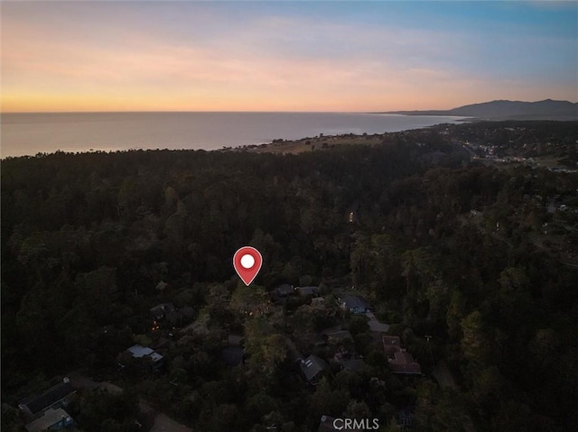 aerial view at dusk with a view of trees and a water and mountain view