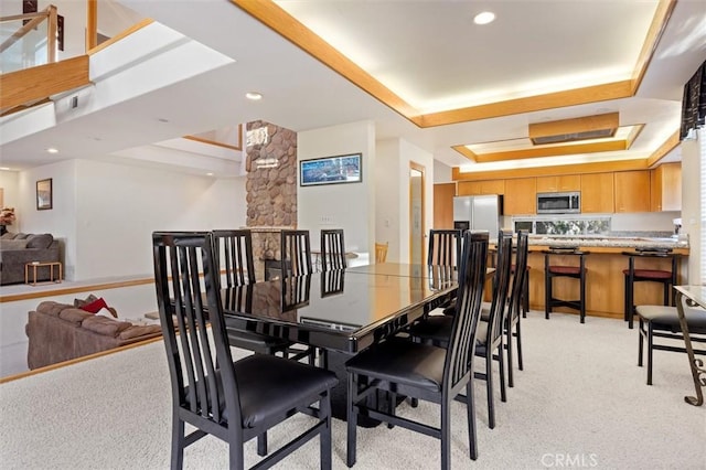 dining area featuring light carpet, a tray ceiling, and recessed lighting