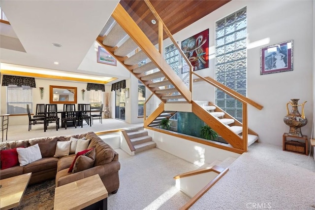 sunken living room featuring carpet, plenty of natural light, and stairs