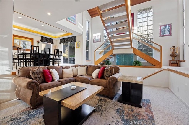 carpeted living area with baseboards, stairway, a raised ceiling, and recessed lighting