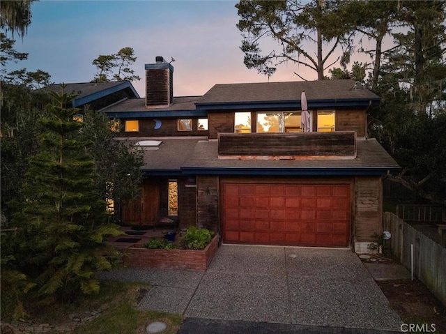 view of front of home with a garage, a chimney, fence, and concrete driveway